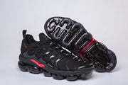 Black and red sneakers with one shoe turned to show the segmented outsole.