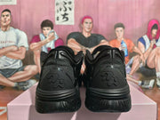 Rear view of a pair of black sneakers showing the heel panels and contoured outsoles.