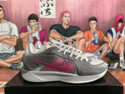 Side profile of a gray Nike basketball sneaker with a pink Swoosh, pink side accents, and a layered outsole.