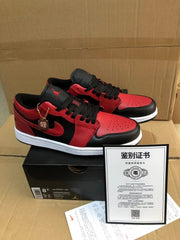 Black and red low-top sneakers displayed on a shoebox beside a printed document; the box label shows Air Jordan 1 Low and sample size 8.5.