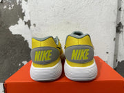 Rear view of yellow Nike sneakers with gray heel tabs and a white ridged sole