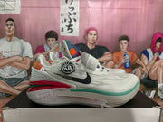 Side profile of a white Nike basketball sneaker with a black Swoosh, circular GT Cut badge, patterned heel, and layered red and green outsole.