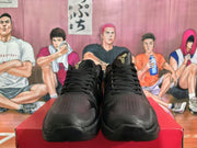 Front view of black basketball sneakers with perforated toe boxes, black laces, and gold tongue emblems.