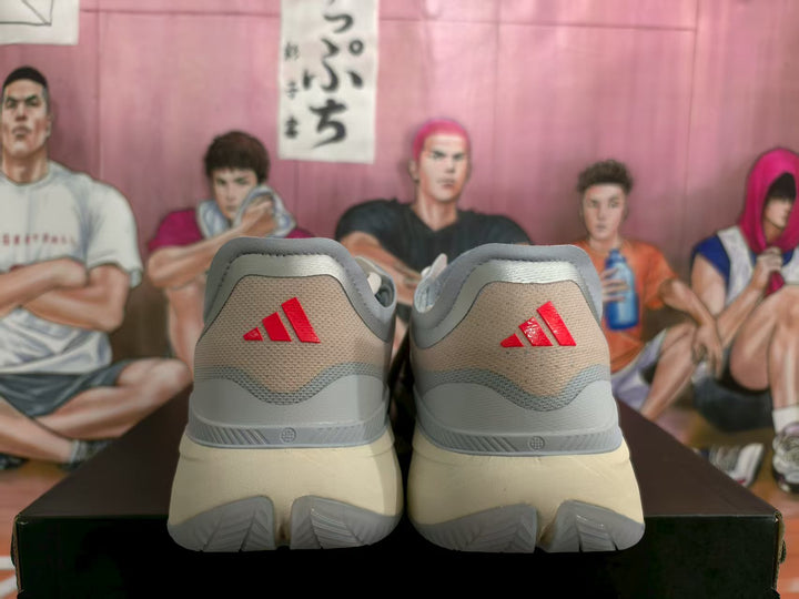Rear view of gray and pale blue adidas basketball shoes with pink heel logos.
