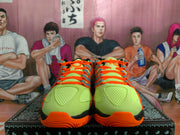 Front view of fluorescent green sneakers with orange laces, orange toe accents, and dark teal side detailing.