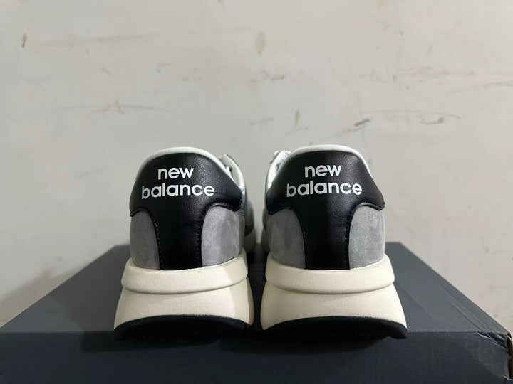 Rear view of gray and white New Balance U370 sneakers with black heel panels.