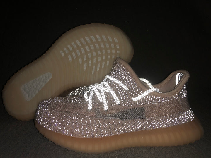 Close-up of the light gray and pink-toned sneaker with reflective-looking laces and a translucent gum-colored sole.