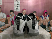 Rear view of the black, white, and gray basketball sneakers showing speckled heel panels, black pull details, and gray outsoles.
