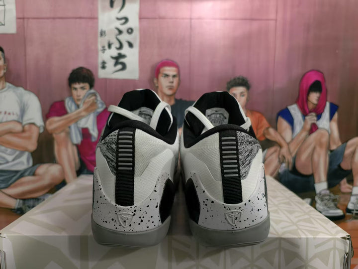 Rear view of the black, white, and gray basketball sneakers showing speckled heel panels, black pull details, and gray outsoles.