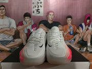Front view of white Nike basketball shoes with black Swoosh accents and pink side details.