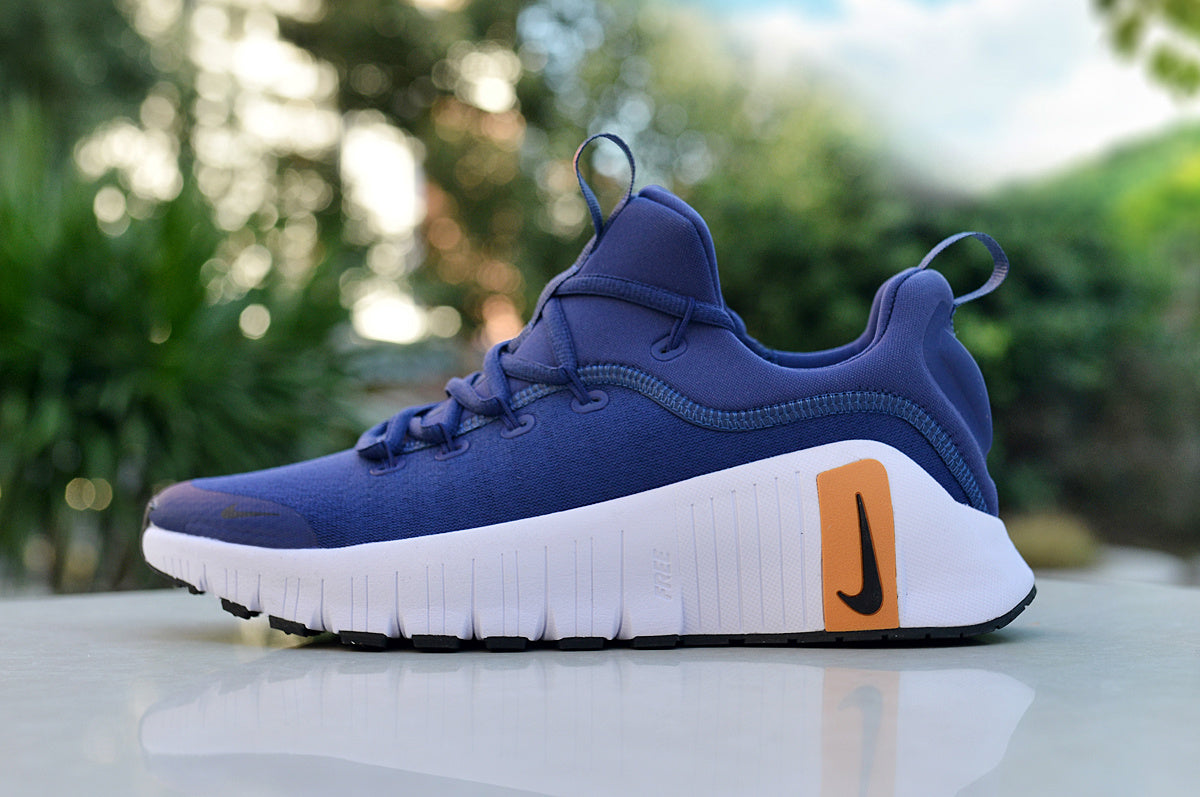 Side view of a blue Nike low-top sneaker with a white sole and orange heel accent.