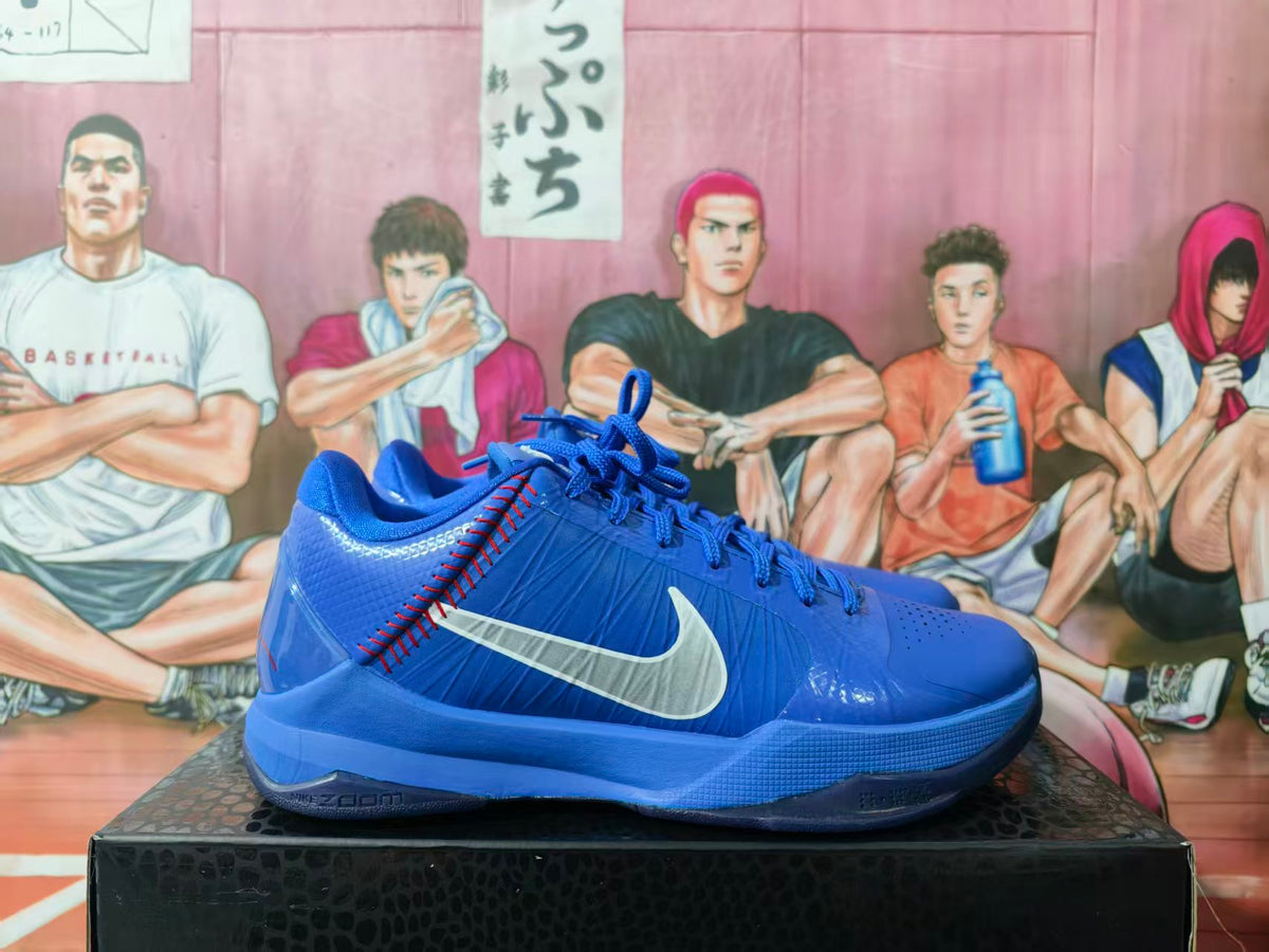 Side view of blue Nike basketball sneakers showing the white side logo, red stitching, perforated toe, and blue outsole.