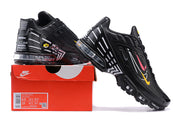 Black Nike Air Max Plus sneakers with colorful side accents displayed on a Nike shoebox; box label shows sample size US Men 9.5 and US Women 11.
