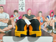 Rear view of the yellow and black sneakers showing black heel panels and textured outsole sections.