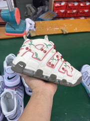 Hand-held view of the cherry-print sneaker in a workshop setting