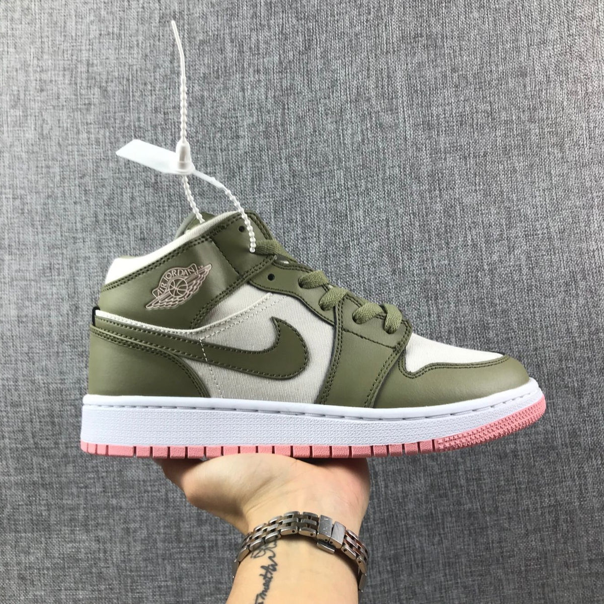 Side view of an olive green, white, and pink Air Jordan 1 Mid sneaker.