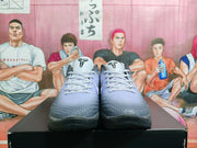 Front view of the black and gray basketball sneakers with white laces, textured toe boxes, and EYBL-style tongue logos.