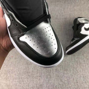 Close-up of the metallic silver perforated toe box framed by black overlays.