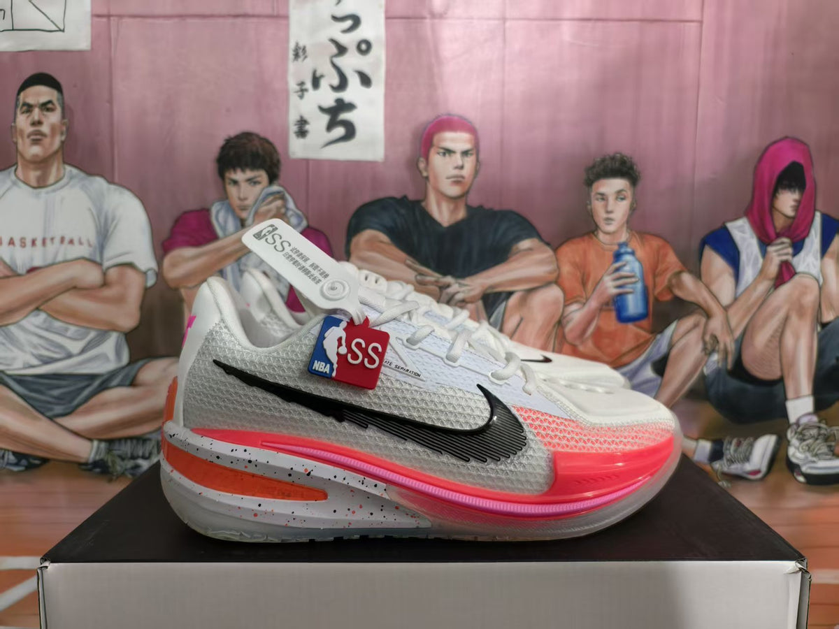 Pair of white Nike basketball sneakers with peach and pink accents, displayed on a shoebox.