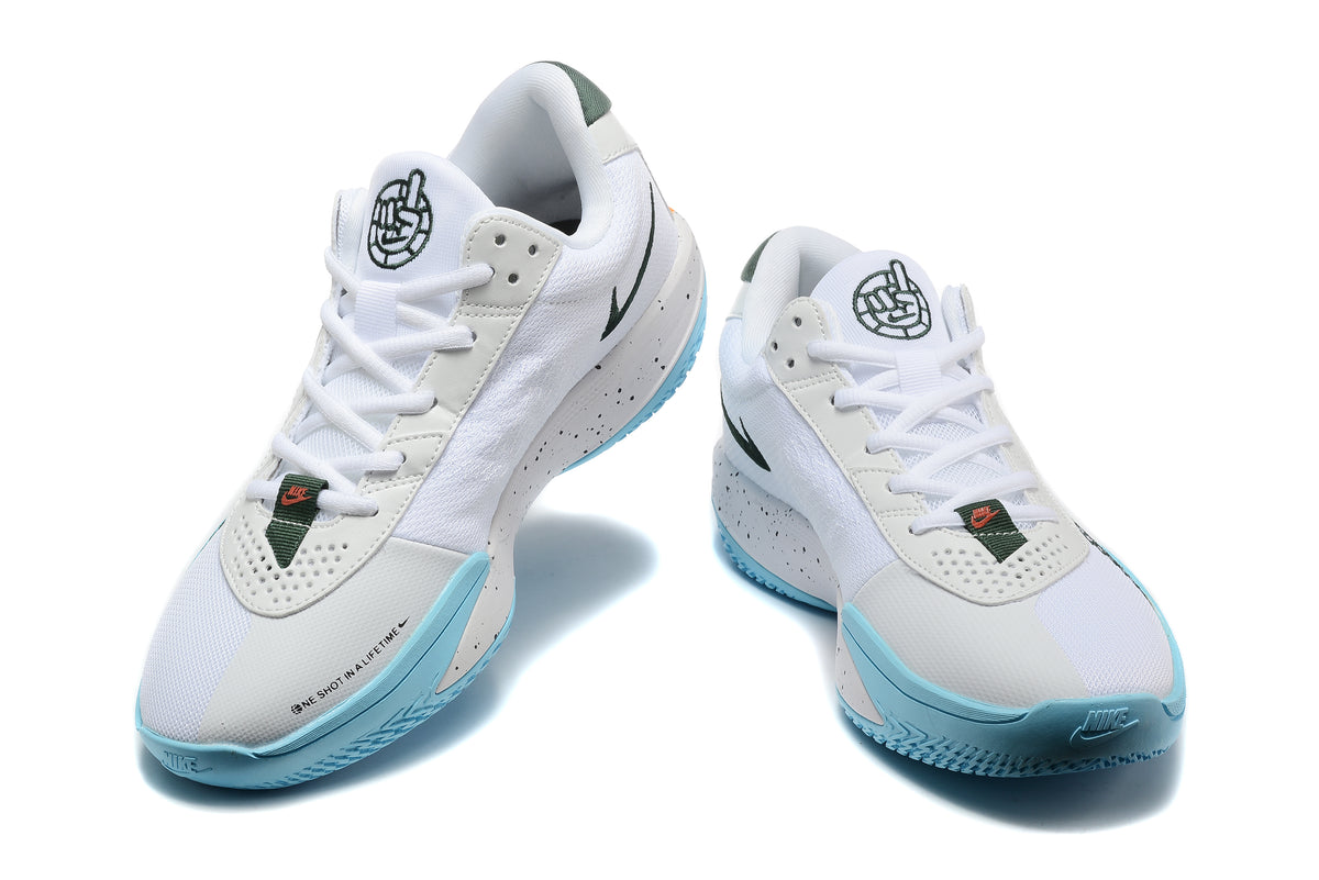 Pair of white Nike basketball shoes with dark green details, light blue soles, and speckled midsoles, shown from the front.