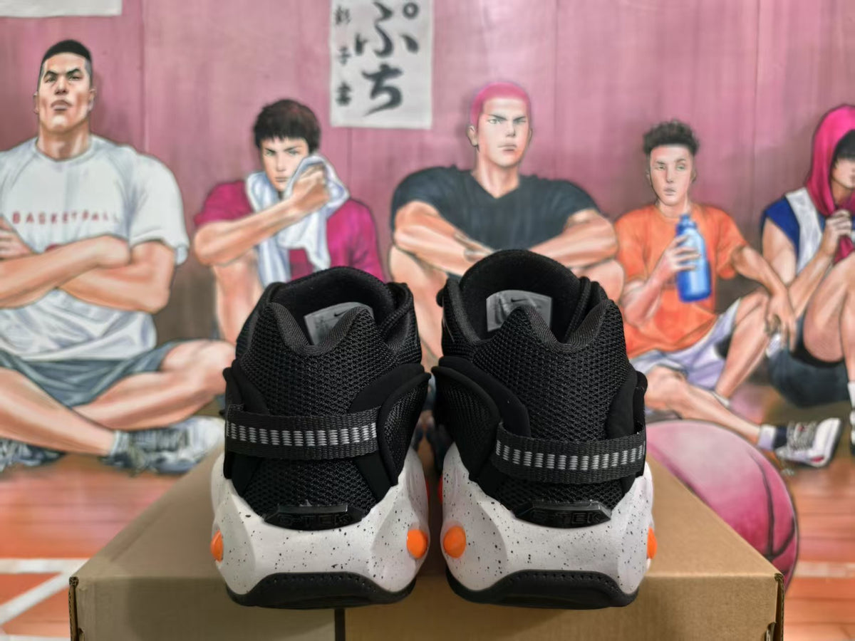 Rear view of black Nike sneakers with textured collars, reflective-looking heel straps, white speckled sections, and orange accents.