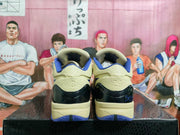 Rear view of beige and blue basketball sneakers showing textured heel panels, black heel sections, and blue outsole accents.