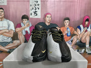 Front view showing the black and white uppers, patterned laces, perforated panels, and small gold-colored swooshes.