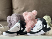 Pair of sneakers posed in front of plush toys, showing the high-top silhouette.