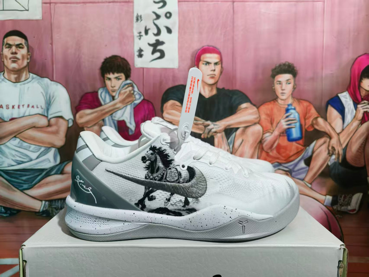 Side view of white and gray Nike basketball sneakers with a dark gray Swoosh, graphic side detailing, and a speckled midsole.