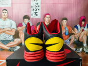Rear view of black basketball shoes with yellow heel panels and red layered outsoles.
