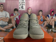 Front view of light gray high-top sneakers with gold-toned tongue details