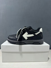 Side profile of a black sneaker with white arrow detail and loose laces.