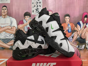 Angled view of black and white Nike sneakers showing contrasting swoosh logos, layered side panels, black laces, and chunky outsoles.