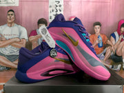 Angled view of the Nike basketball shoe pair showing the pink upper, purple overlays, gray side panel and gold Swoosh.