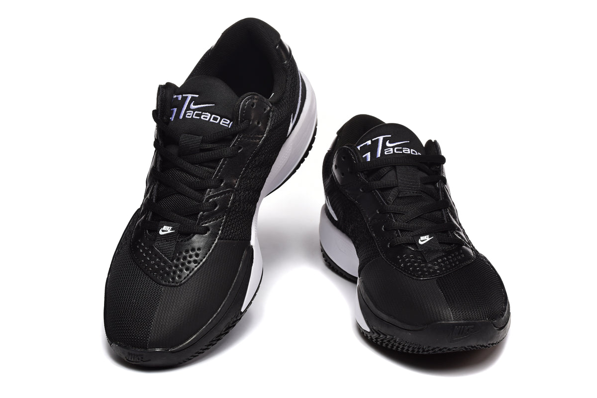 Pair of black and white Nike sneakers shown from the front with lace-up closures and contrasting white midsoles.
