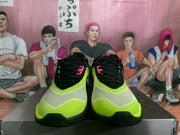 Front view showing the green toe areas, black laces, pink accents, and black outsoles of the Nike sneakers.