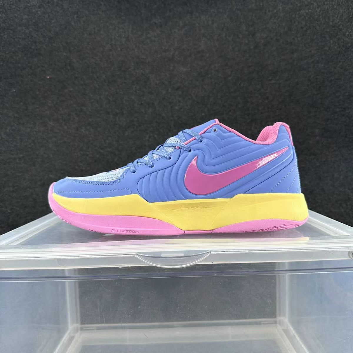 Side view of a blue Nike basketball sneaker with a pink swoosh and outsole and a yellow midsole section.
