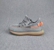 Side view of a gray and coral Yeezy 350 V2 kids' sneaker with a translucent amber-toned sole.