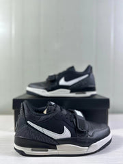 Angled side view highlighting the white side detailing, textured heel panel, strap, and layered black and white midsole.