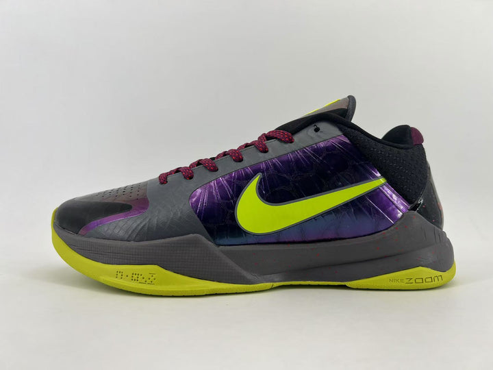 Side view of a dark gray Nike basketball shoe with purple panels, a lime Swoosh and lime outsole.