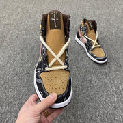 Front view showing the brown perforated toe box, cream laces, black paisley overlays, and padded collar.