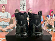 Rear view of a pair of black high-top basketball sneakers showing padded collars, glossy heel panels and layered outsoles.
