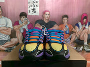 Front view showing the paired purple Nike sneakers, yellow mesh toe panels, blue laces, and black outsoles.