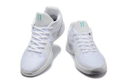 Pair of white Nike Sabrina basketball shoes shown from the front with teal tongue accents.