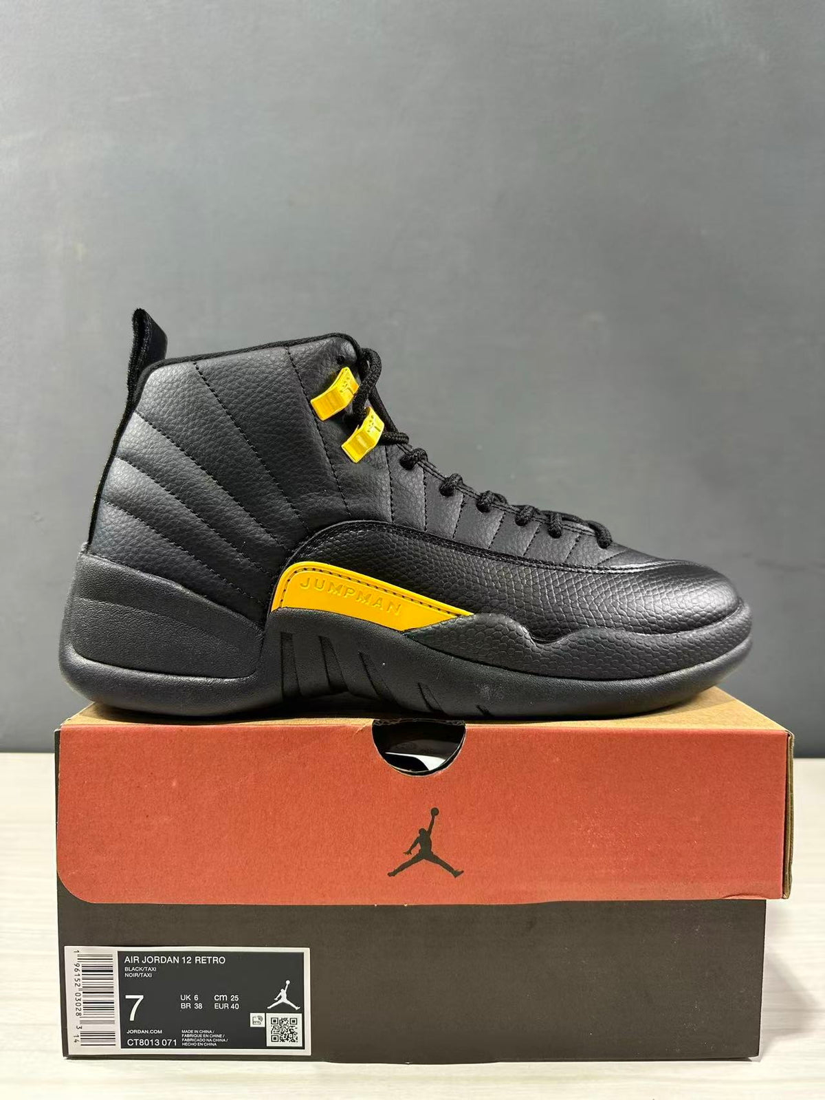 Side view of a black and yellow Jordan Air Jordan 12 Retro sneaker displayed on its shoebox; the box label shows size 7, EU 40 and style code CT8013-071.