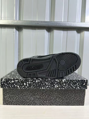 Black sneaker outsole shown from below with concentric forefoot tread and geometric rubber traction sections.