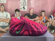 Side view of a pink Nike basketball sneaker with a contrasting green Swoosh, purple patterned upper, and visible Zoom branding.