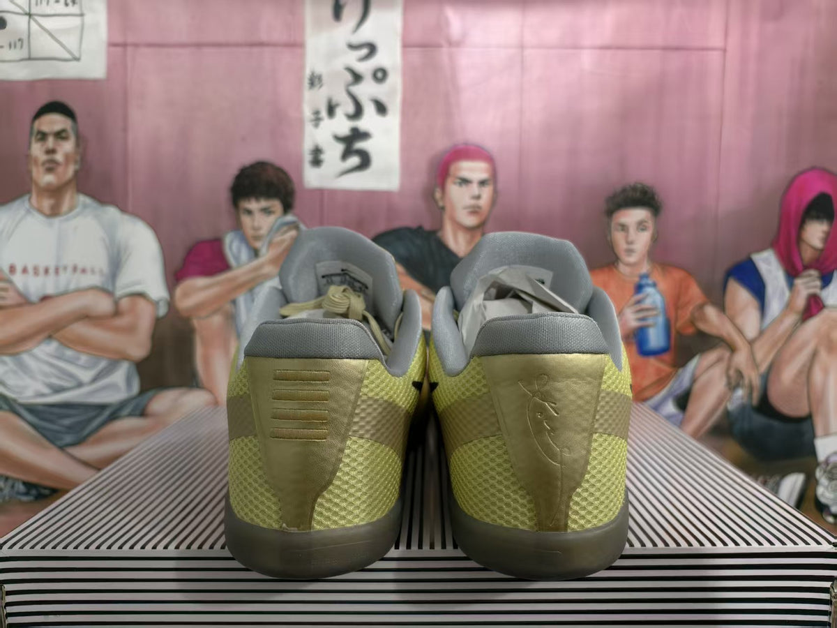 Rear view of gold-toned Nike basketball shoes showing padded gray collars, textured panels and dark translucent outsoles.