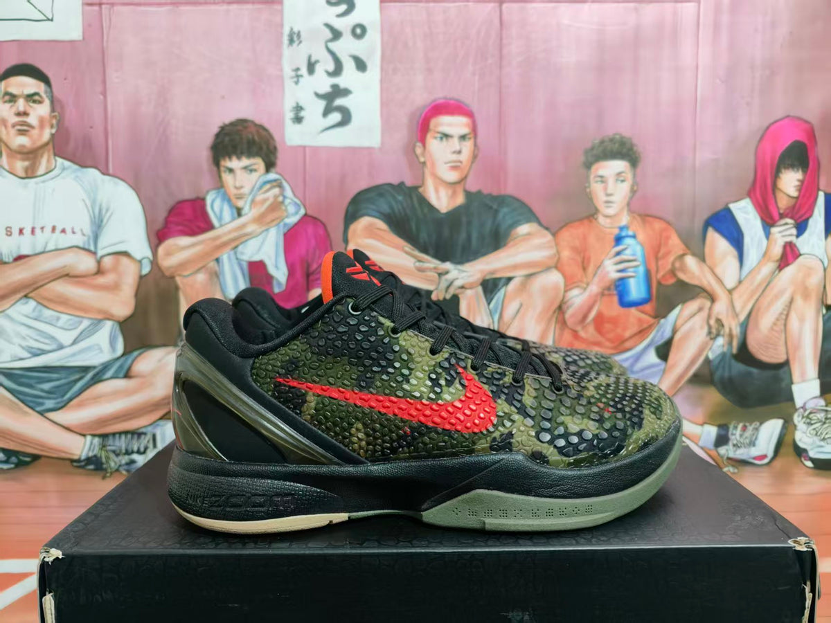 Side view of green and black camouflage Nike basketball-style sneaker with red Swoosh detailing on a shoebox.