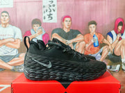 Side profile of a black and gray Nike sneaker showing the layered textured upper, side Swoosh, laces, and rugged-looking sole.